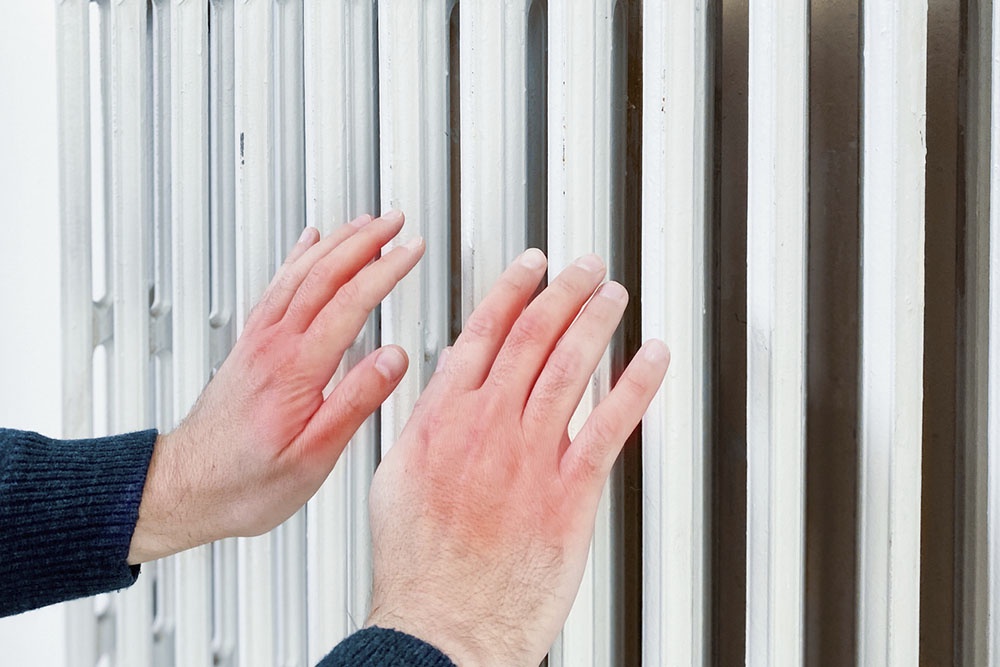 Сухие руки на фоне отопительной батареи