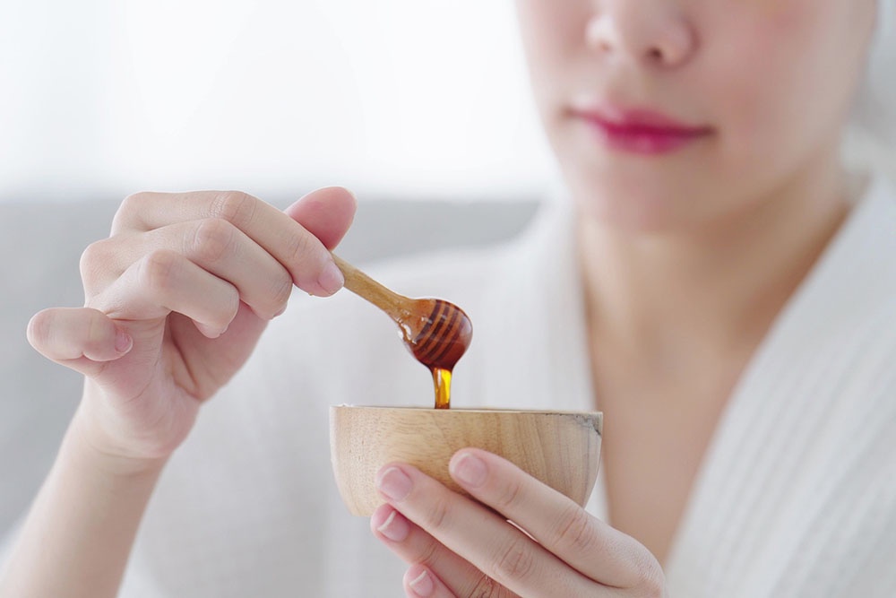 Девушка держит мед в руках, собирается использовать мед для косметических процедур