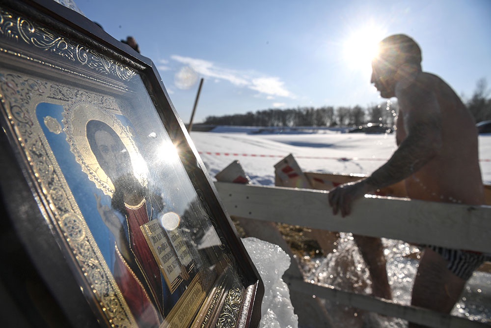 Мужчина окунается в иордань во время празднования Крещения 