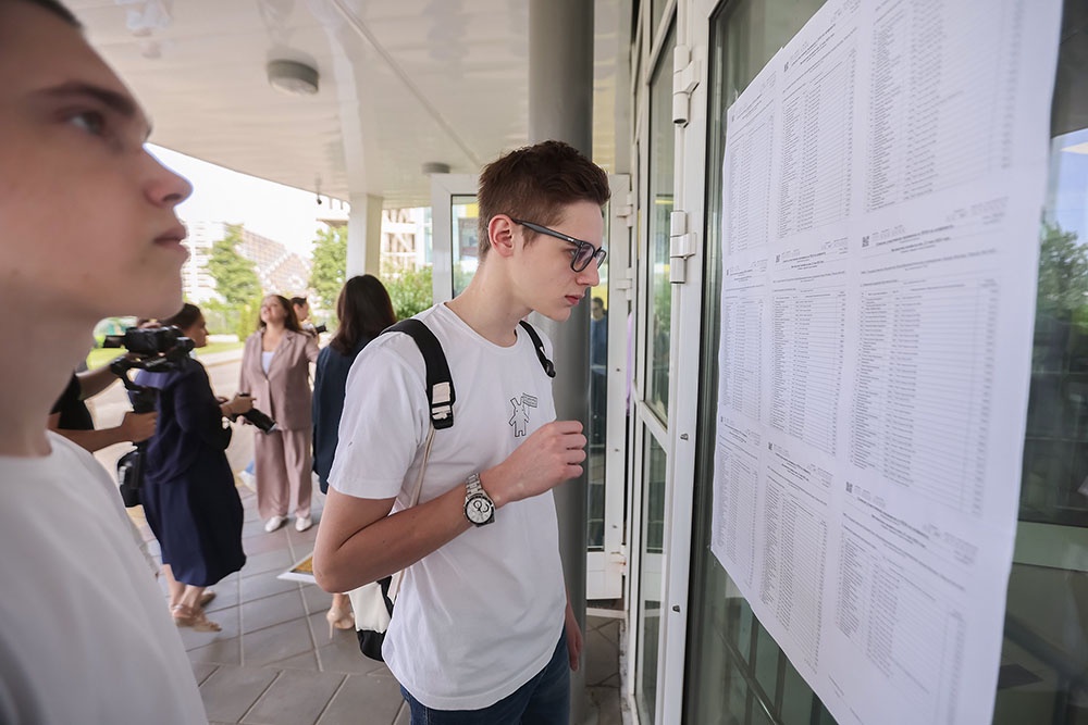 Выпускники читают списки, вывешенные в пункте проведения экзамена (ППЭ), перед началом ЕГЭ.