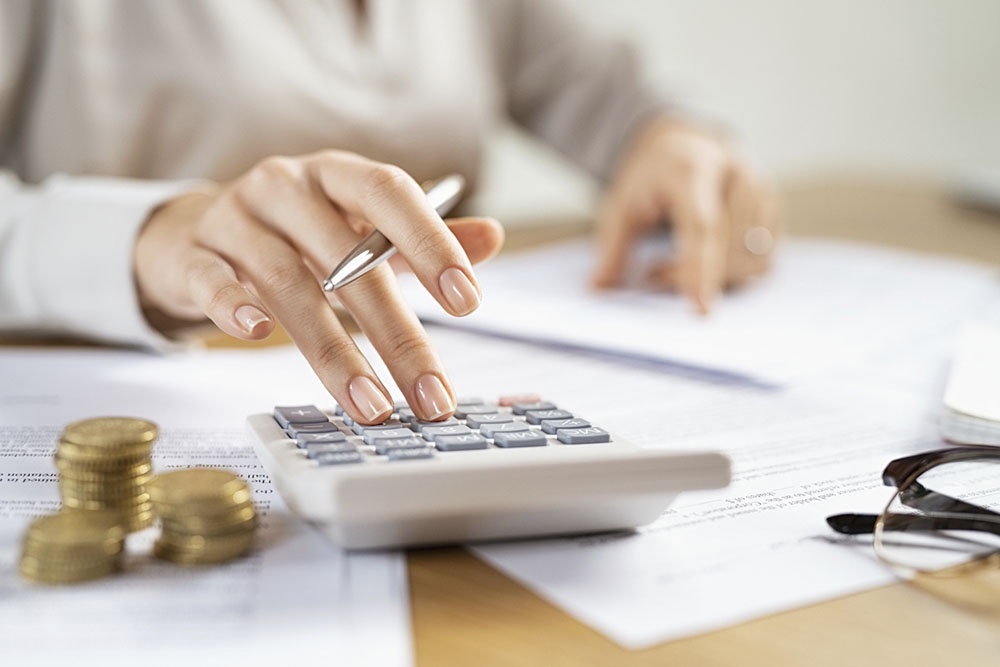 Человек пересчитывает  на калькуляторе сумму и сравнивает условия договора