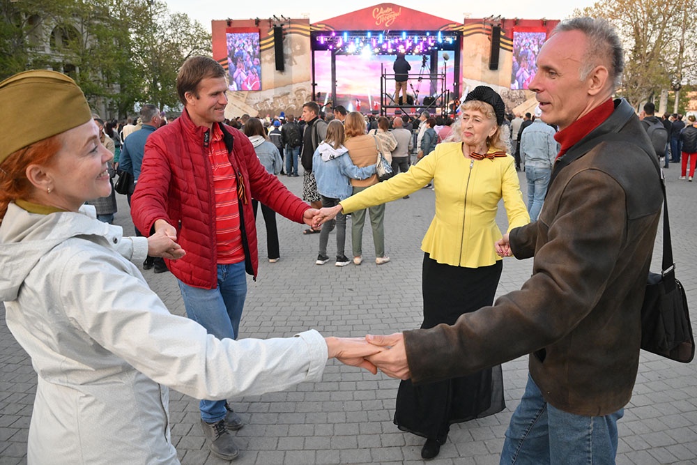 Люди танцуют взявшись за руки