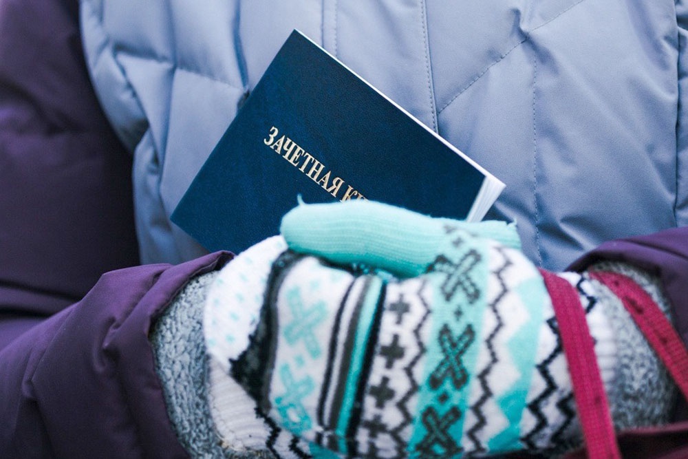 Студентка держит в руках  студенческий билет