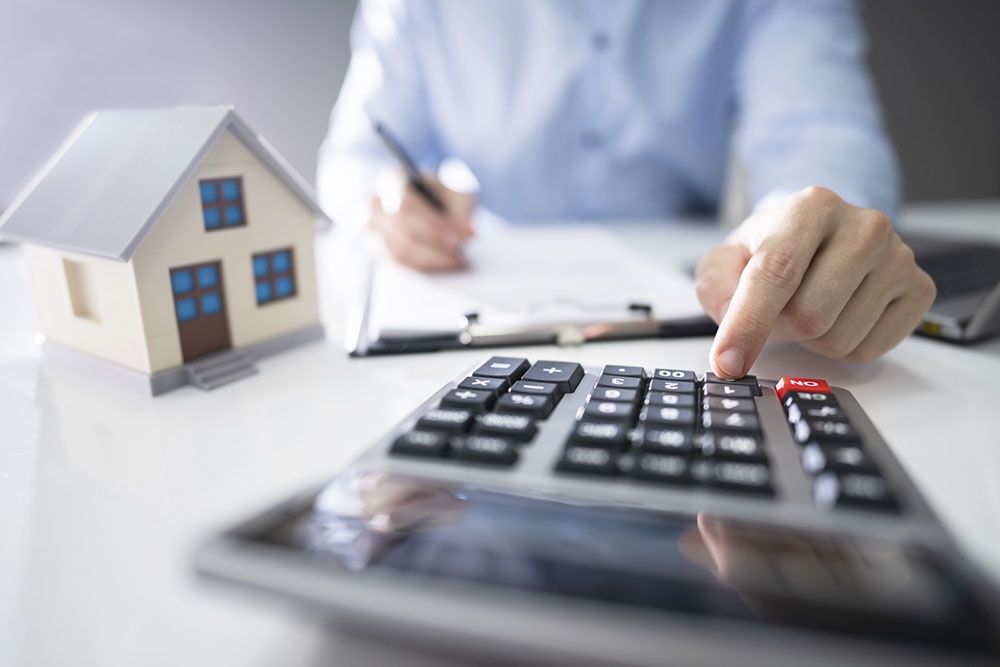 Человек считает на калькуляторе сумму платежа по ипотеке