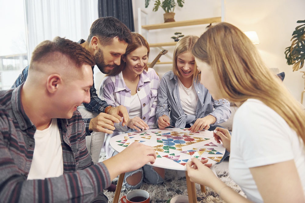 Друзья, юноши и девушки, играют в настольную игру.