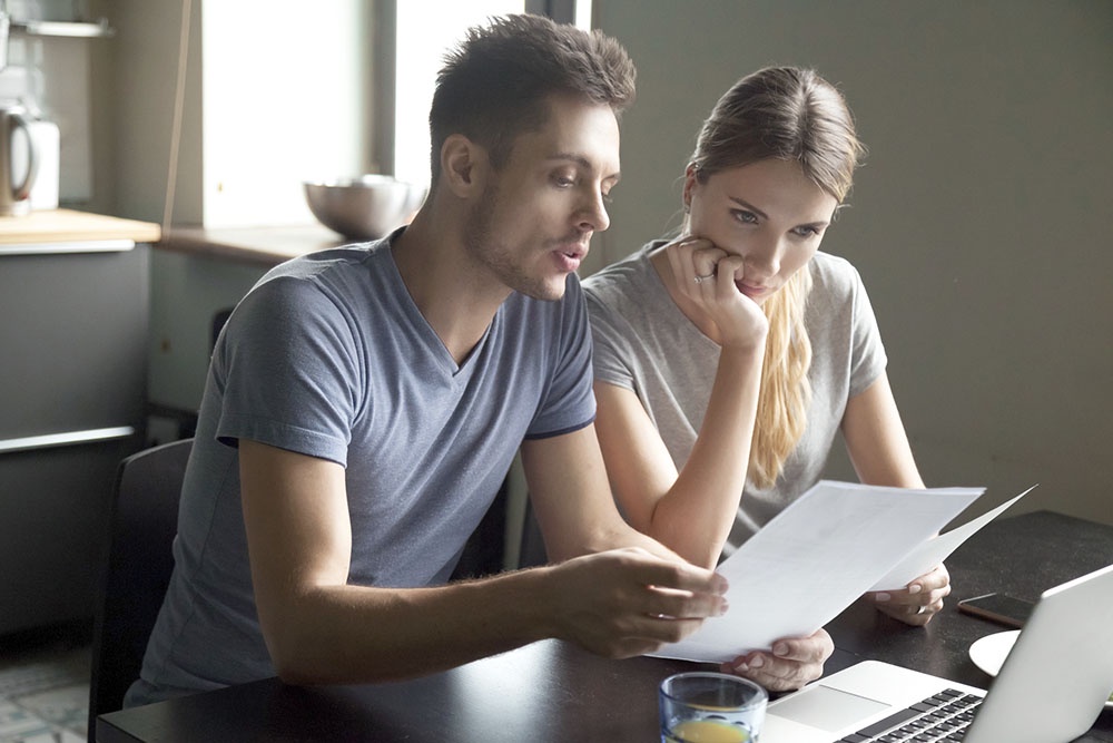 Кредиторы (муж и жена) изучают документы и условия кредитного договора.