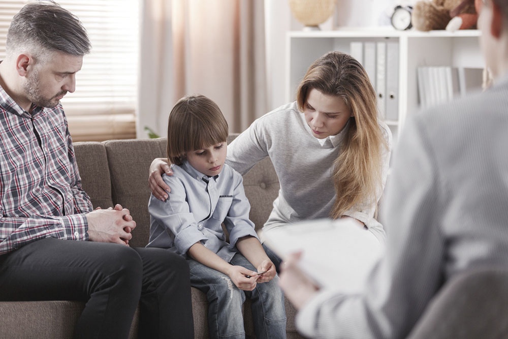 Семейная консультация психолога, родители и ребенок обсуждают вопросы во время сеанса.