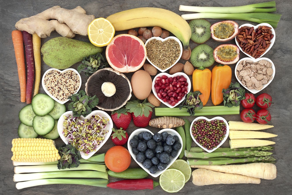 Вид сверху: композиция из полезных продуктов, богатых нутриентами - свежие овощи, фрукты, орехи и рыба.