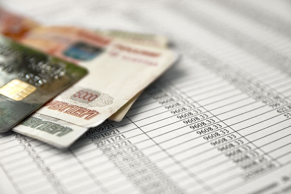 Деньги и распечатанный график платежей по ипотечному кредиту.