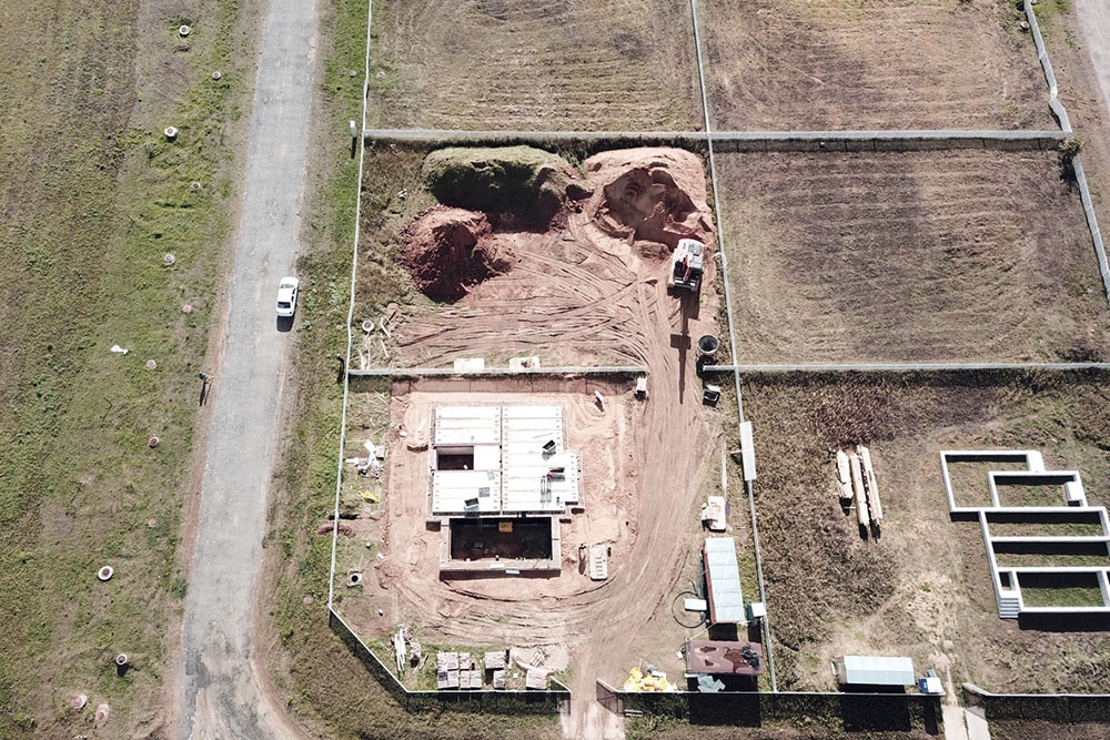 Вид сверху на организованную строительную площадку с четким зонированием.