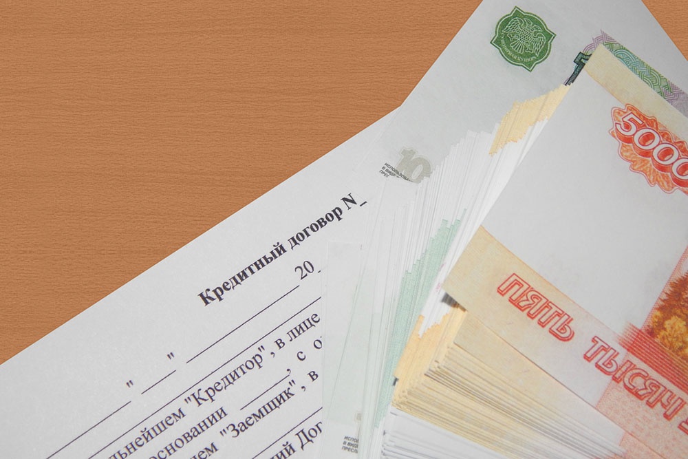 Кредитный договор и стопка наличных денег лежат на столе.