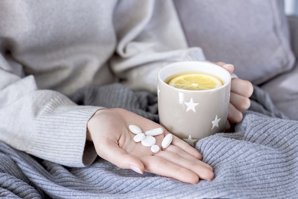 Девушка держит в руках горсть таблеток.