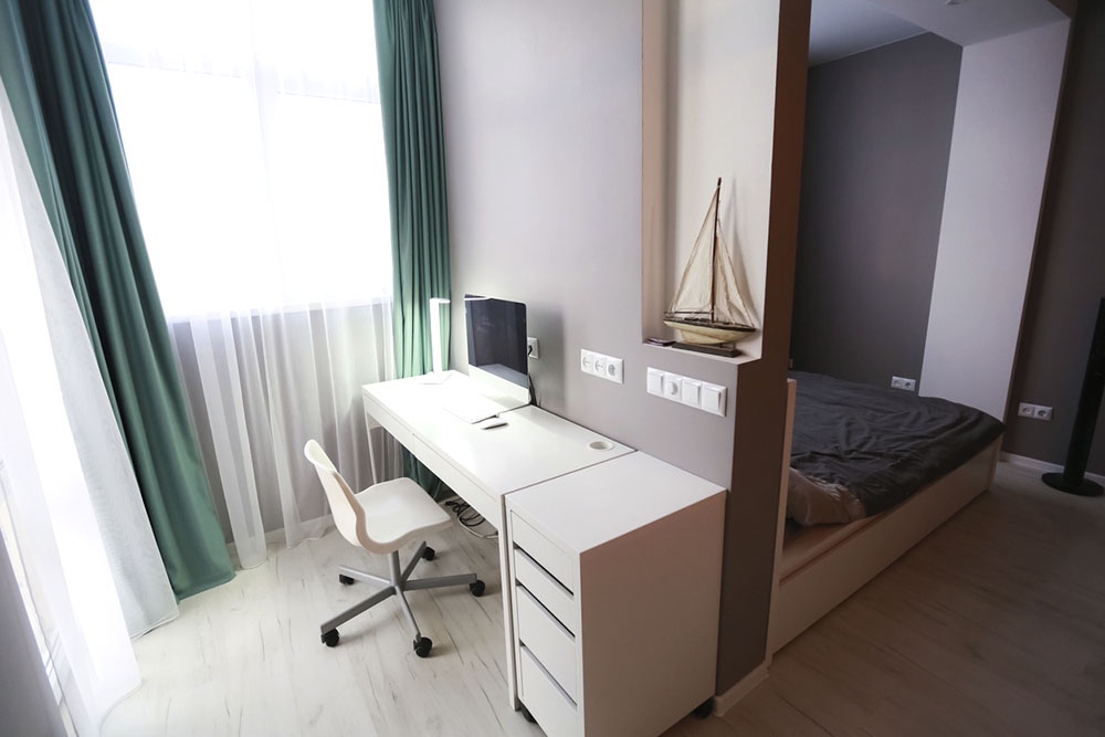 Зонирование комнаты, рабочее место с компьютерным столом отделено от спальной зоны с кроватью.