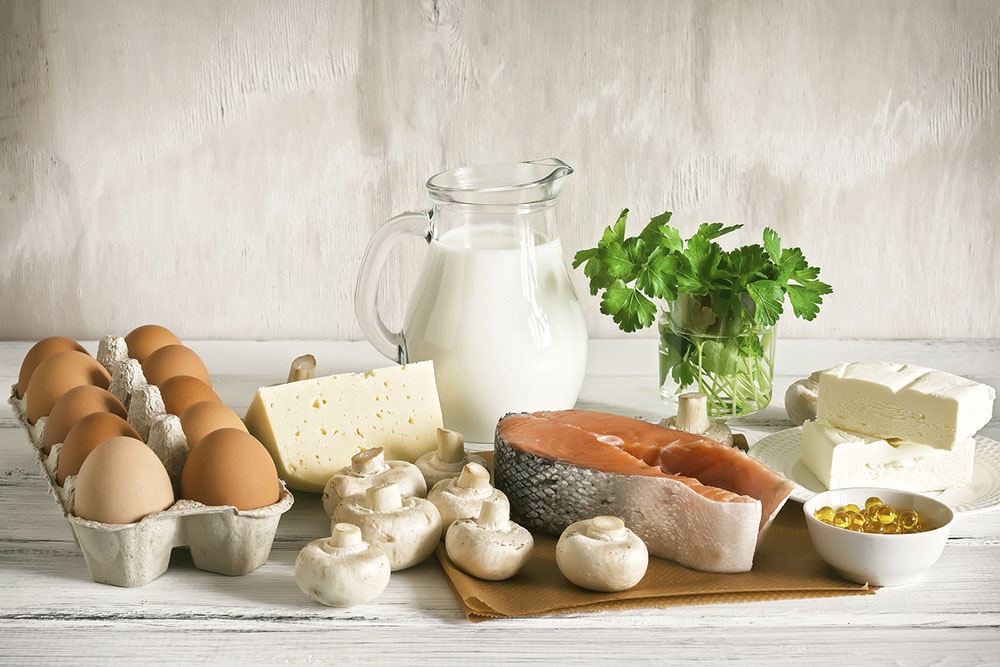 Набор продуктов для правильного питания и иммунитета: молоко, рыба, сыр, творог, петрушка и яйца на столе.