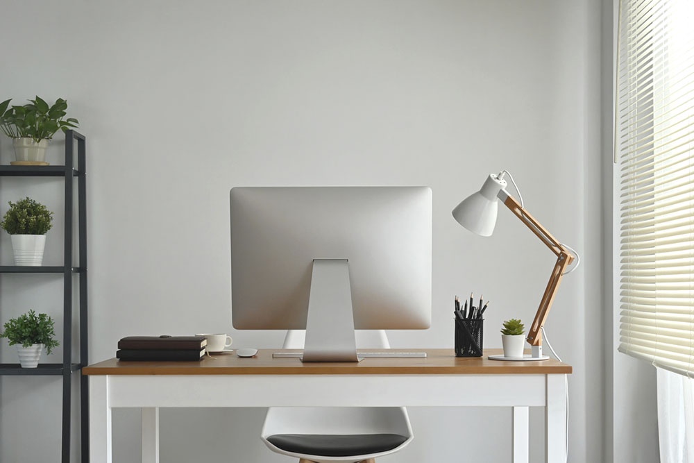 Эргономичное рабочее место: письменный стол расположен у окна так, чтобы дневной свет падал сбоку.