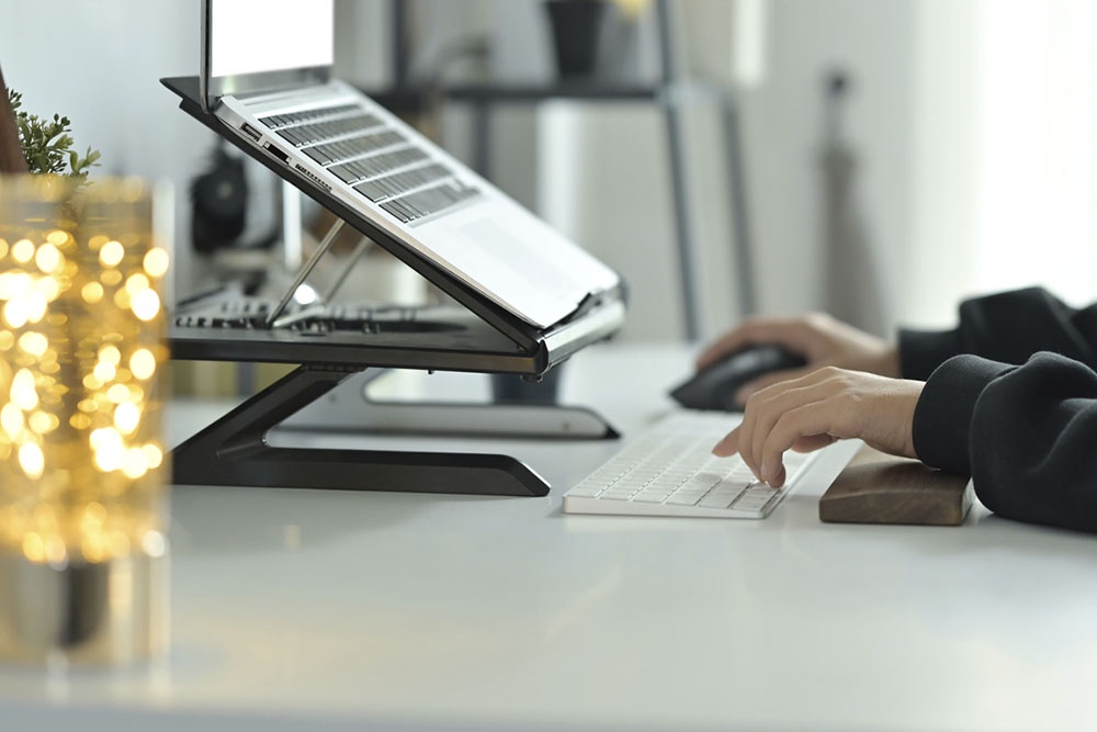 Организованное рабочее место с ноутбуком на подставке и выносной клавиатурой для эргономики.