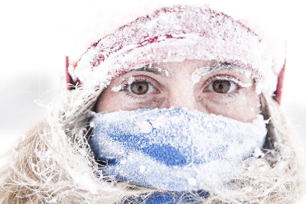 Человек на морозе прикрывает нос и рот шарфом, защищая дыхательные пути от холода.