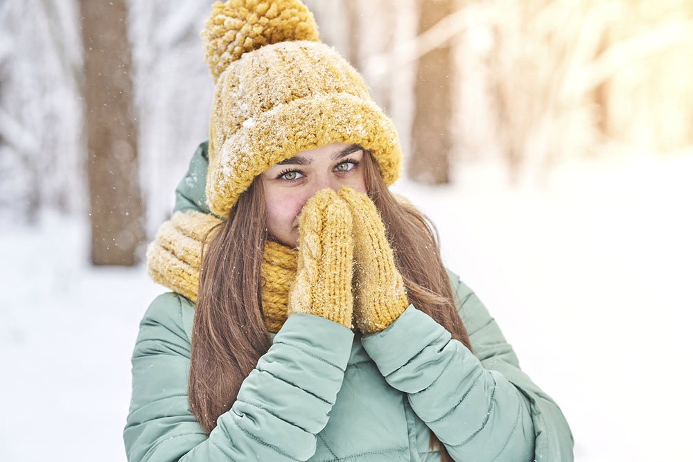Девушка на зимней прогулке в полной экипировке -  шапка, шарф и варежки.