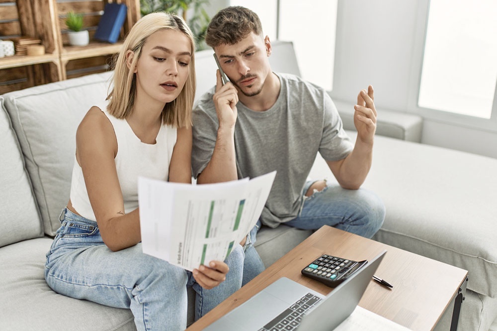 Муж и жена изучают документы, опасаясь отказа в ипотеке из-за отсутствия первоначального взноса.