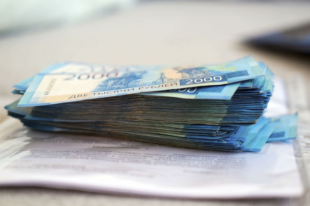 Стопка денег и документы, подтверждающие расходы по ипотеке (платежки, выписки из банка), на столе.