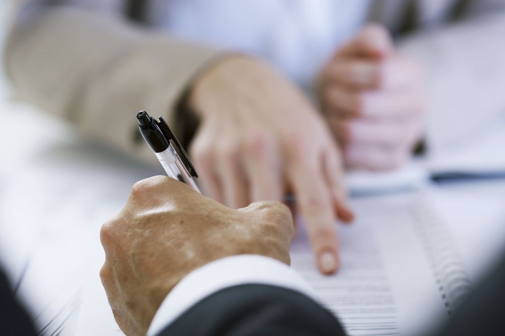 Сотрудник подписывает документы у работодателя для получения имущественного налогового вычета.