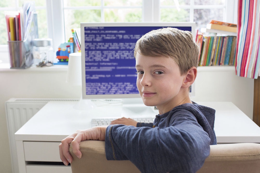 Подросток за компьютером изучает программирования.