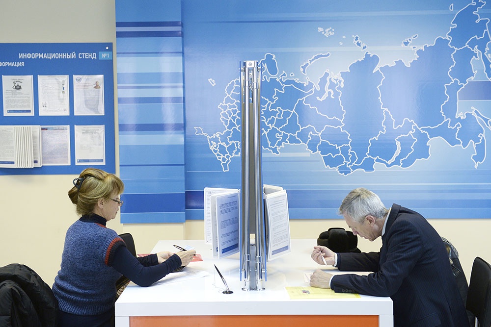 Посетители оформляют документы в офисе налоговой службы.