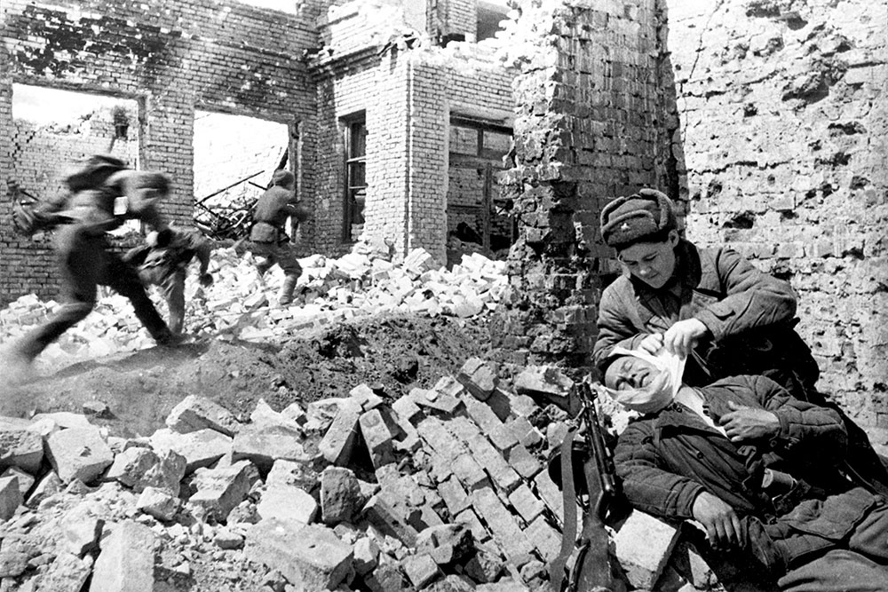 Санинструктор оказывает первую медицинскую помощь раненому красноармейцу в ходе уличных боев за Сталинград.