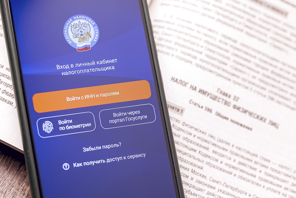 Налоговый кодекс и телефон с приложением ФНС на столе.