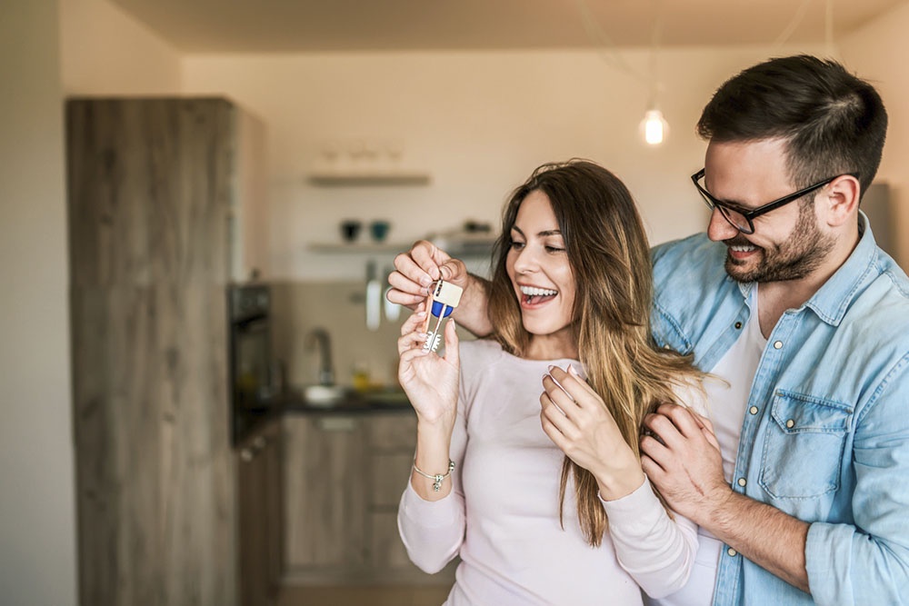 Муж дарит жене ключи от квартиры с ипотекой, иллюстрируя дарение между супругами с особыми налоговыми условиями.