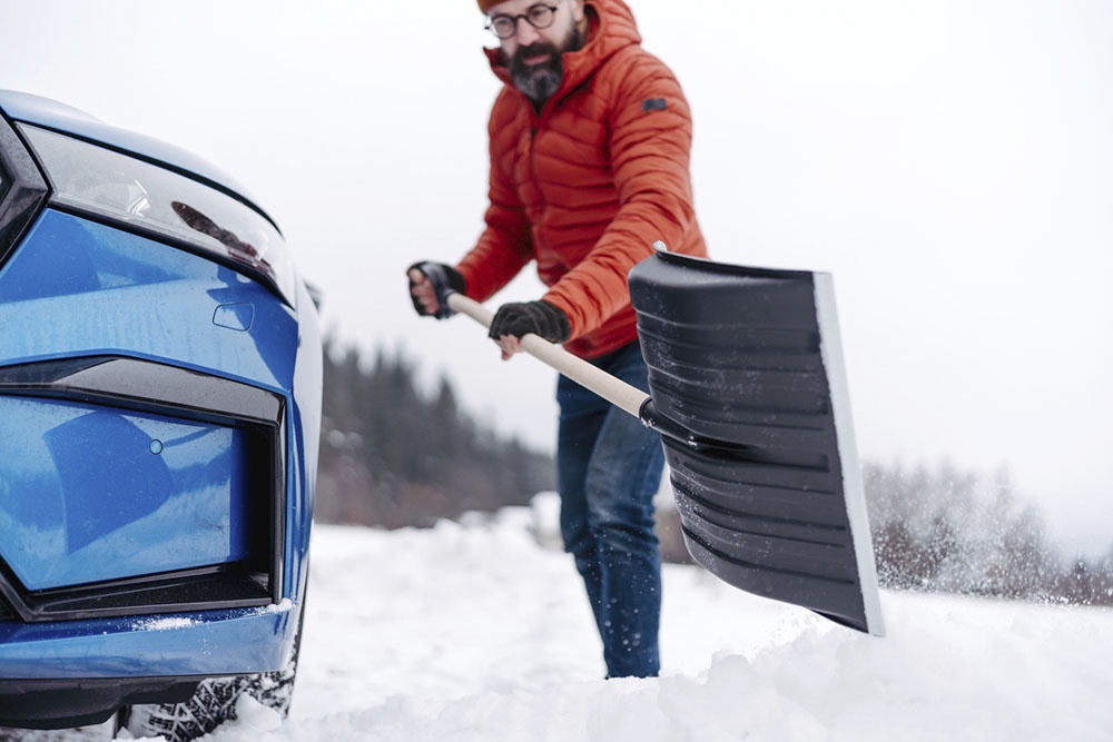 Мужчина в зимней одежде правильно отбрасывает снег лопатой: спина прямая, ноги согнуты, движение идет от бедер.