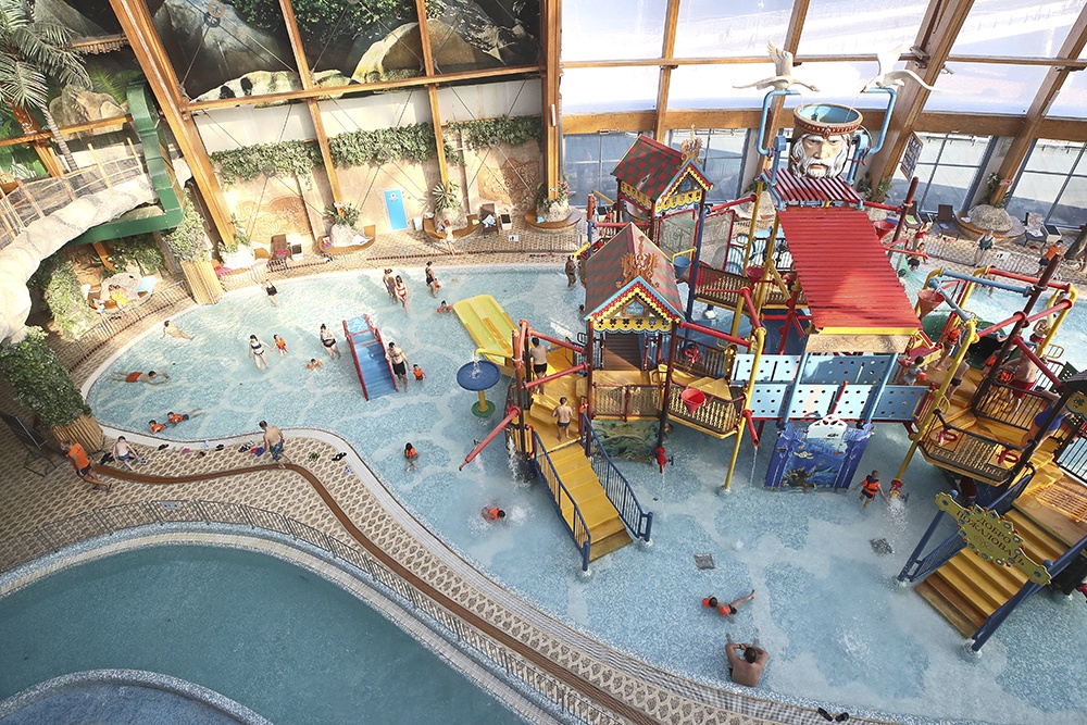 Общий вид на внутреннюю территорию аквапарка "Питерлэнд" с посетителями на фоне.
