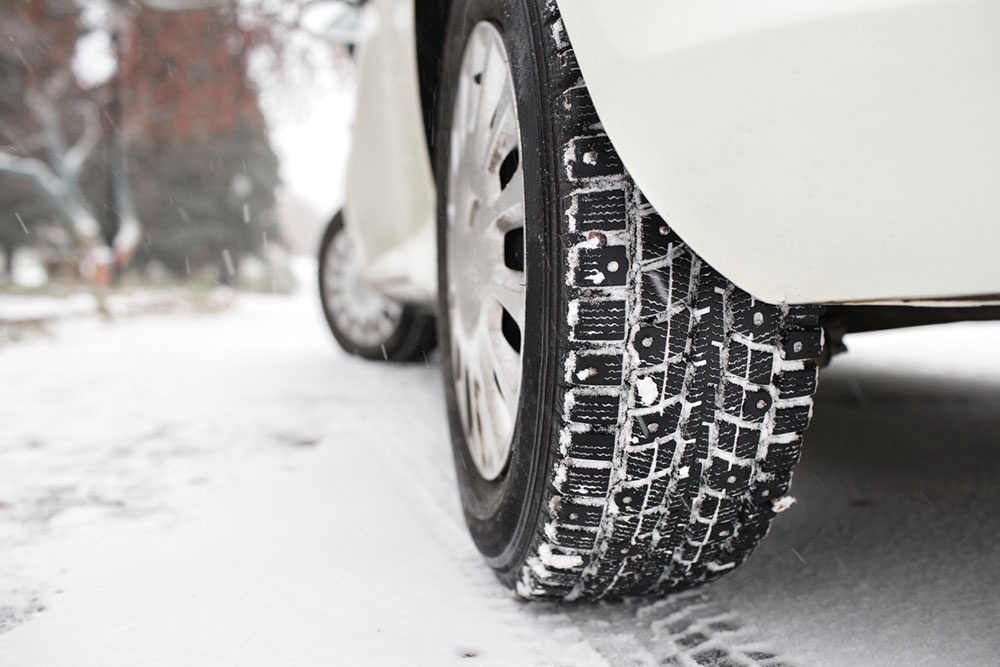 Автомобиль медленно и плавно начинает движение вперед по укатанной снежной колее, без пробуксовки.