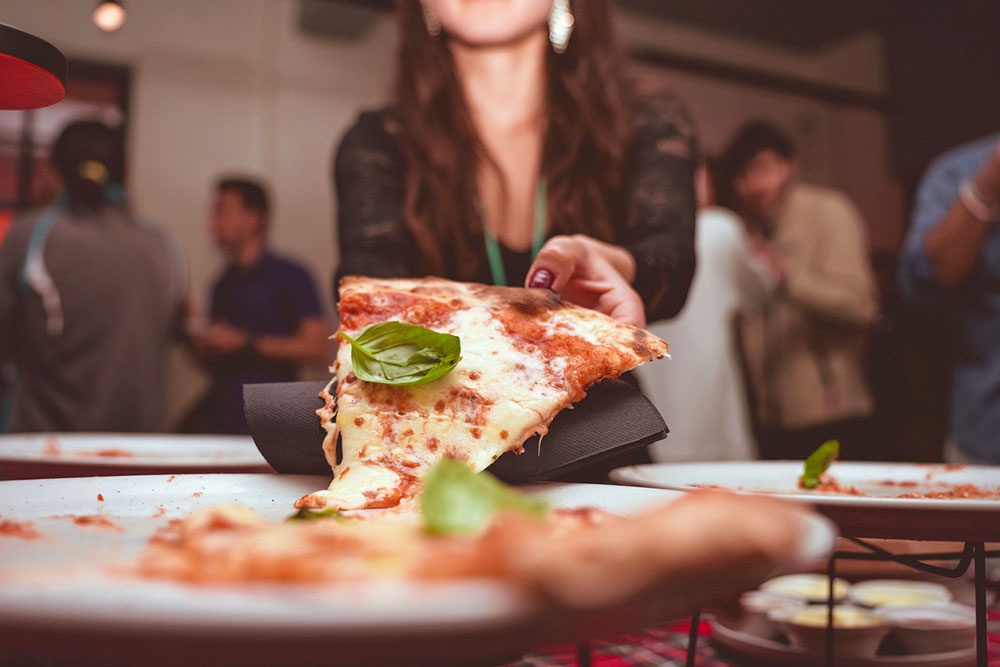 Посетительница в пиццерии отмечает праздник, ест кусочек пиццы.