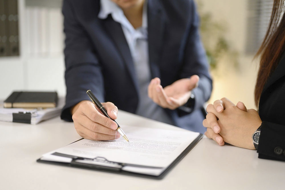 Два человека подписывают документы за столом.