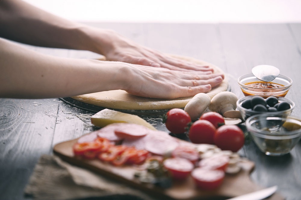 Идеально круглая, тонкая лепешка из теста для пиццы, лежащая на столе.