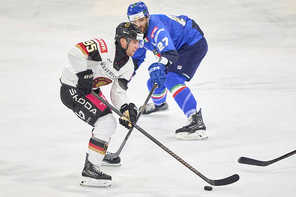 Фредерик Тиффельс (Германия) против Томаса Ларкина (Италия) в борьбе за шайбу в товарищеском матче перед Олимпиадой-2026.