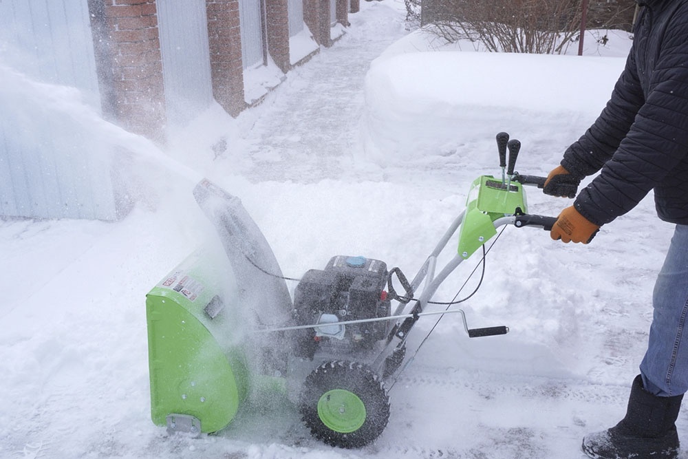 Большой бензиновый самоходный снегоуборщик легко расчищает снег.