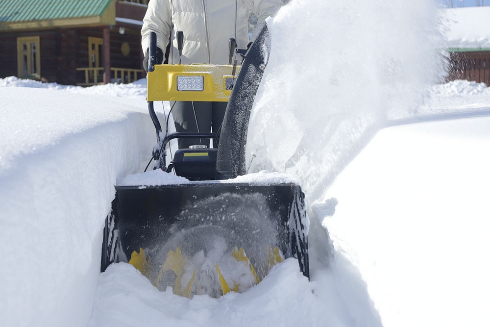 Крупный план, шнек мощного снегоуборщика проделывает дорожку в высоком снежном покрове