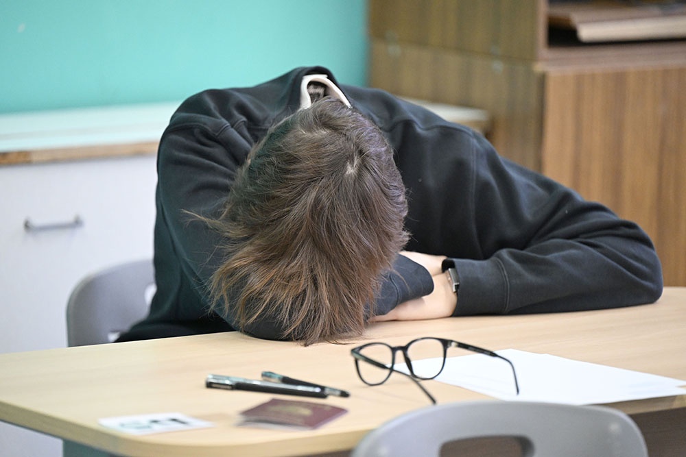 Школьник на ЕГЭ по английскому опустил голову на руки, размышляя над сложным заданием.