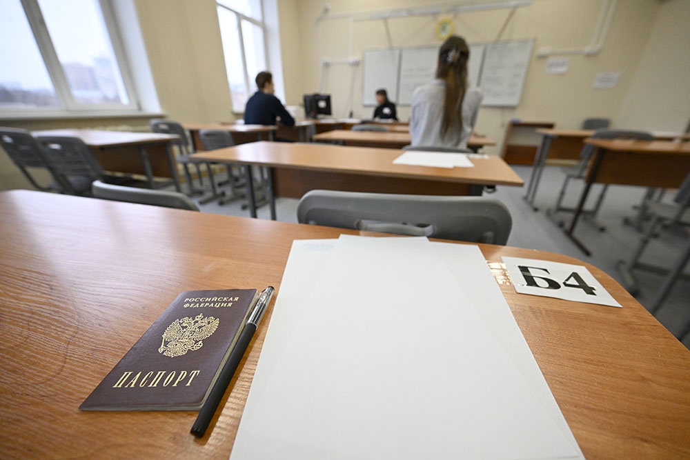 Школьники в экзаменационной аудитории на ЕГЭ по английскому языку. на столе документы и чистый лист бумаги.