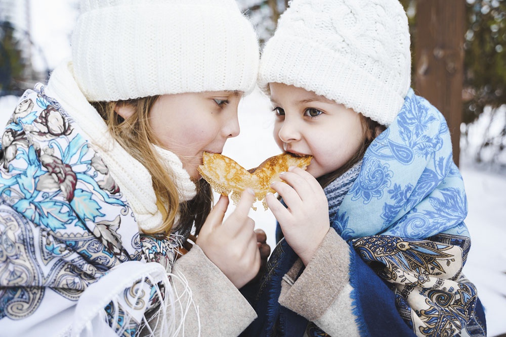 Дети едят блины на Масленицу.