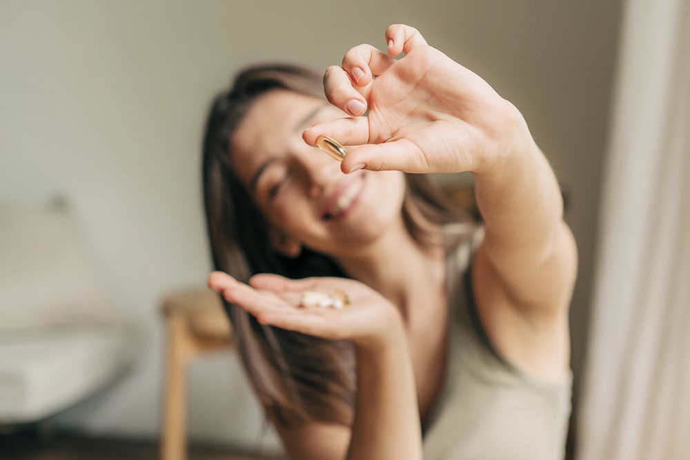 Девушка пьет витамины зимой.