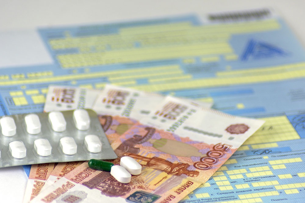 Больничный лист и рубли на столе.