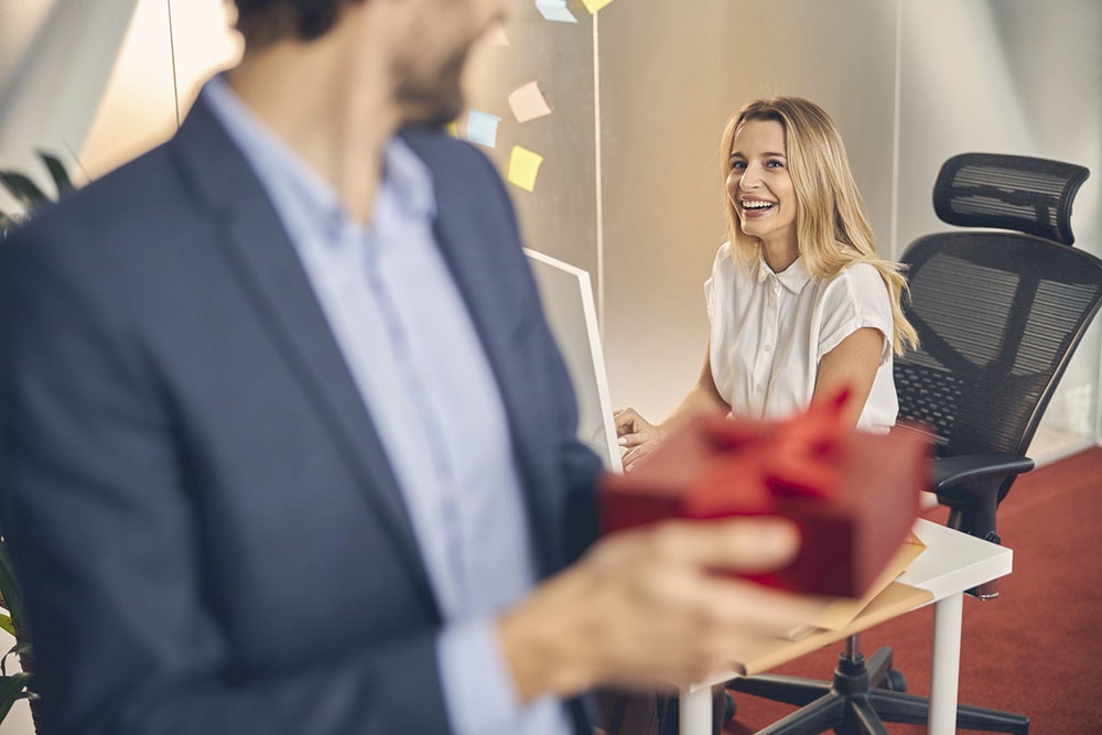 Поздравление коллег в офисе. Мужчина с подарочной коробкой.