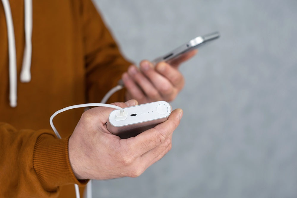 Мужчина держит в руке пауэрбанк.