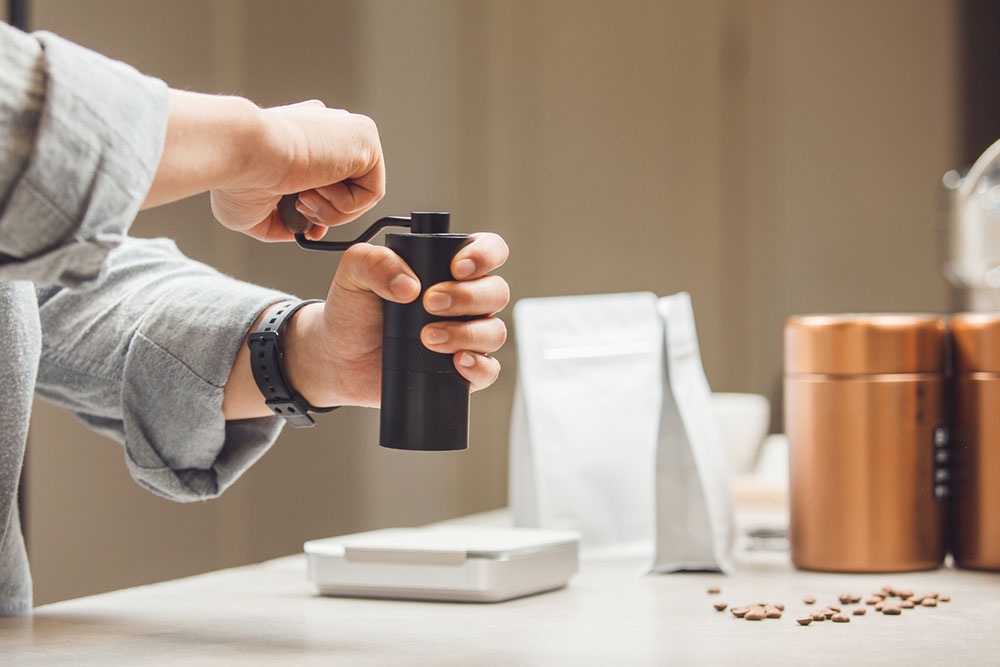 Мужчина перемалывает кофе в современной кофемолке.