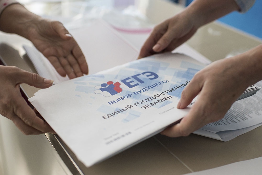 Конверт с задание ЕГЭ по биологии в руках у педагогов.