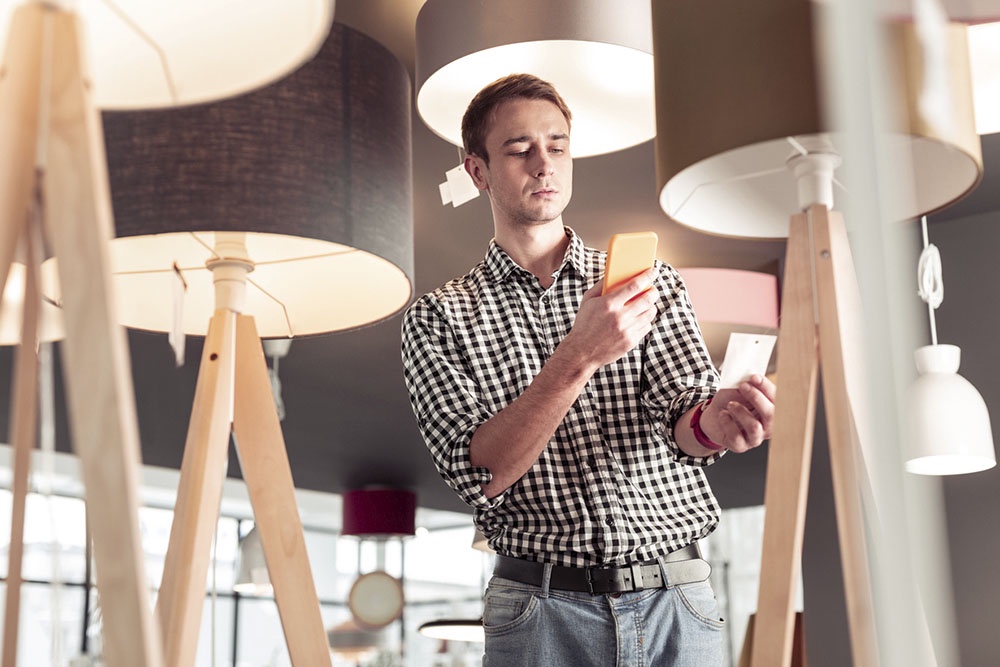 Мужчина выбирает настольную лампу в магазине.