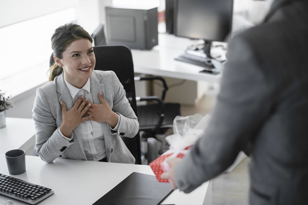 Мужчина дарит коллеге женщине подарок  на 8 Марта.